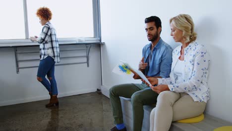 Male-and-female-executives-discussing-over-digital-tablet