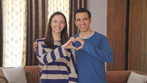 cute indian couple making heart gesture