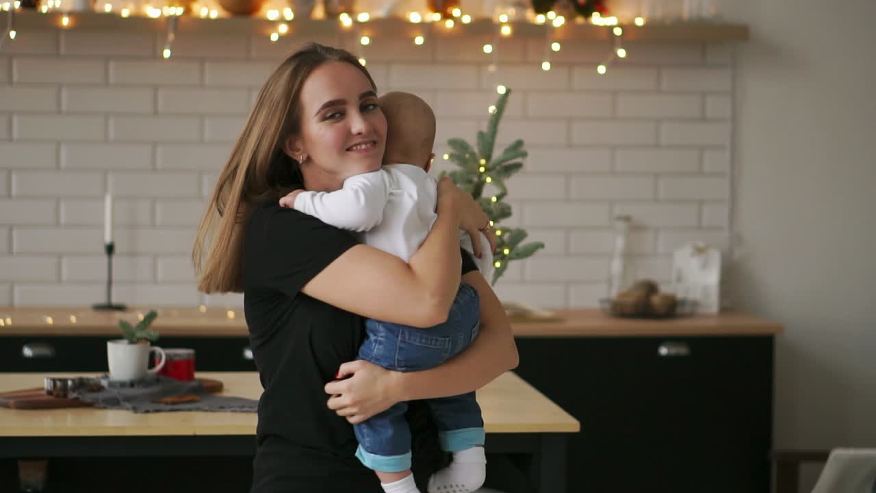 Young Mother Holding her Newborn Child slow motion. Family at home, mom and baby boy for christmas