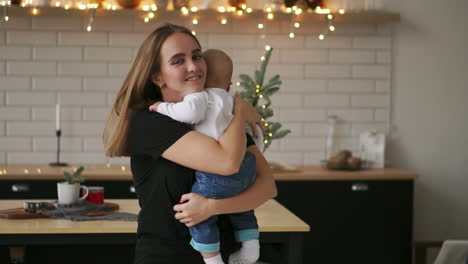 young mother holding her newborn child slow motion. family at home, mom and baby boy for christmas