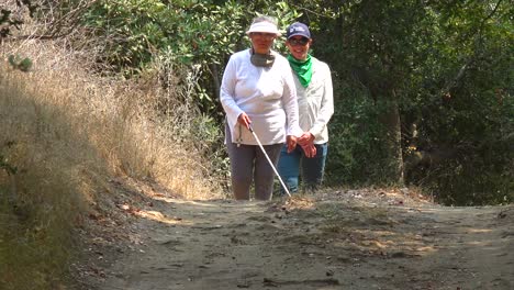 una mujer ciega camina con un bastón por un área natural con un guía que la ayuda a explorar el desierto 1