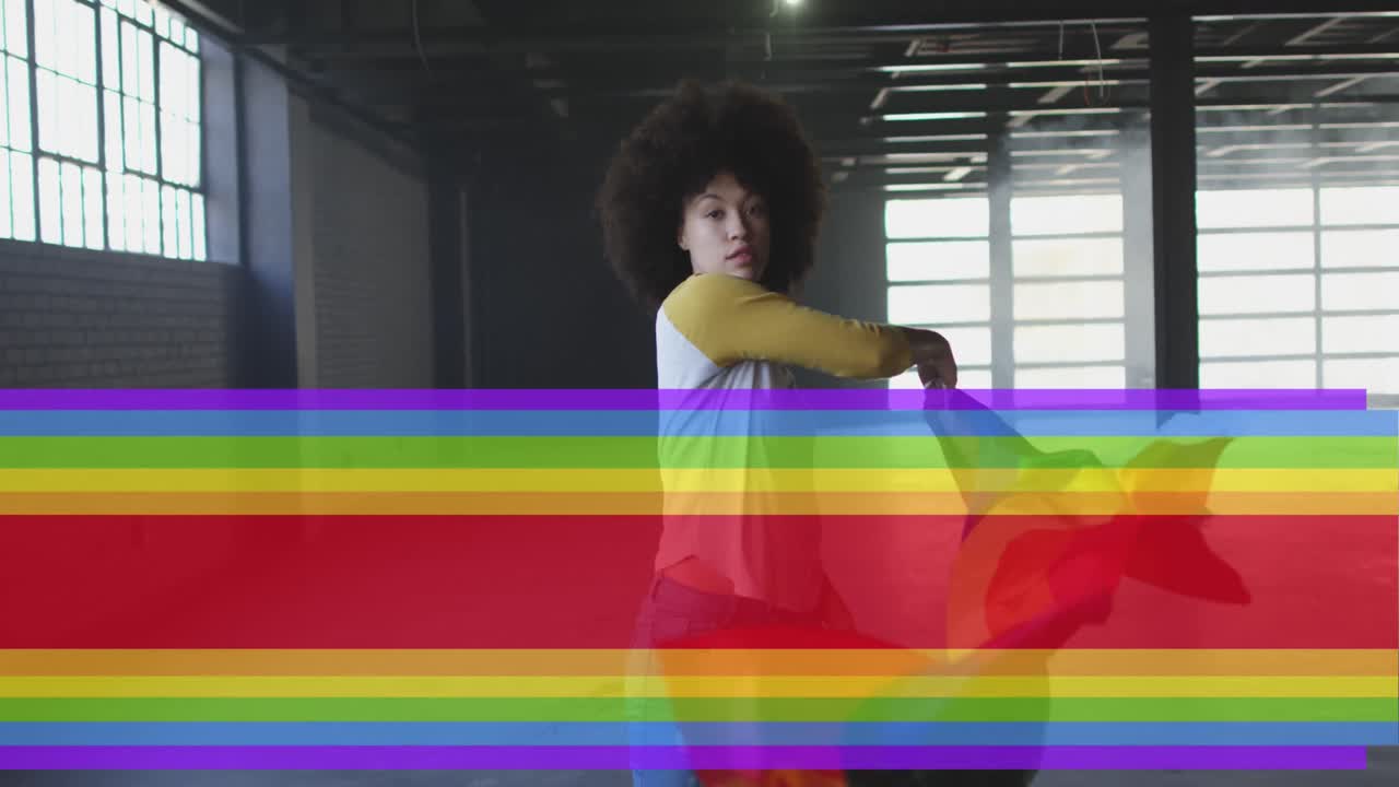 Animation of rainbow flag over african american woman waving with flag
