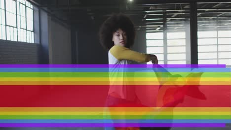 animation of rainbow flag over african american woman waving with flag