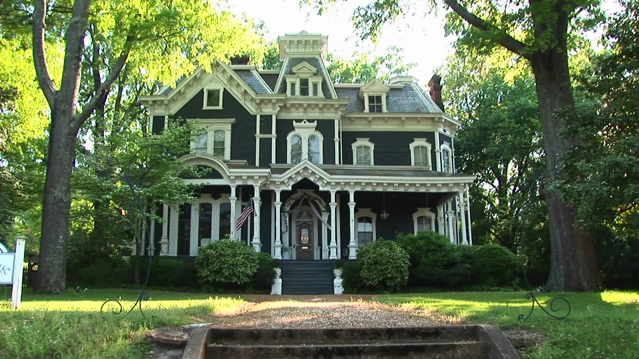 사랑스러운 오래된 집은 큰 잎이 무성한 푸른 나무로 둘러싸여 있습니다