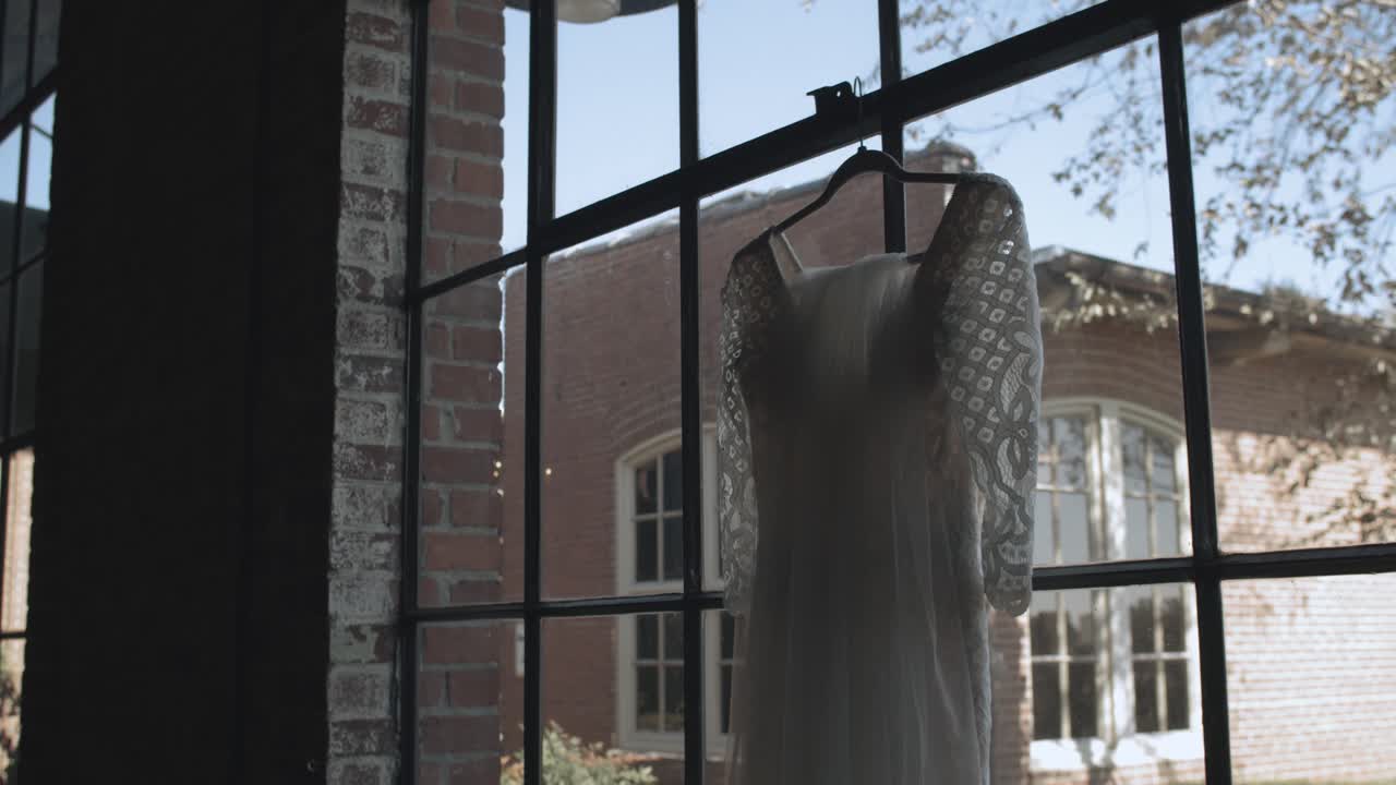 Ready Wedding dress hanging on hanger inside window of beautiful location