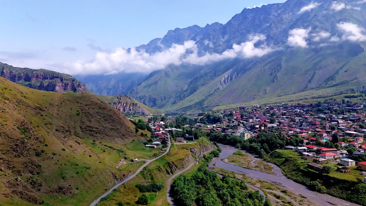Georgian town in scenic mountainous river valley, aerial Hyperlapse with cinematic dynamic clouds