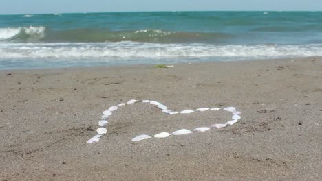 bubbly wave washes over stone pebble heart in sand 1