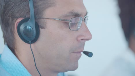 focused male call center worker in headset taking call