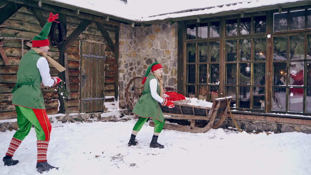 Couple of elves are playing snowballs running aroud a backyard. Holidays. Christmas eve. New year is coming. Winter landscape