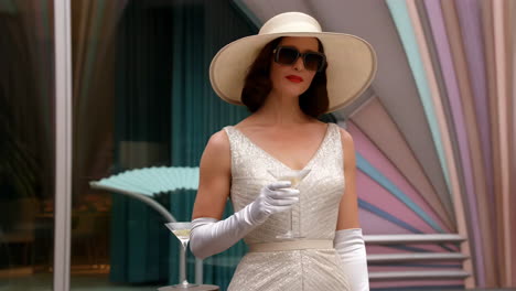 elegant woman in hat and sunglasses holding a martini