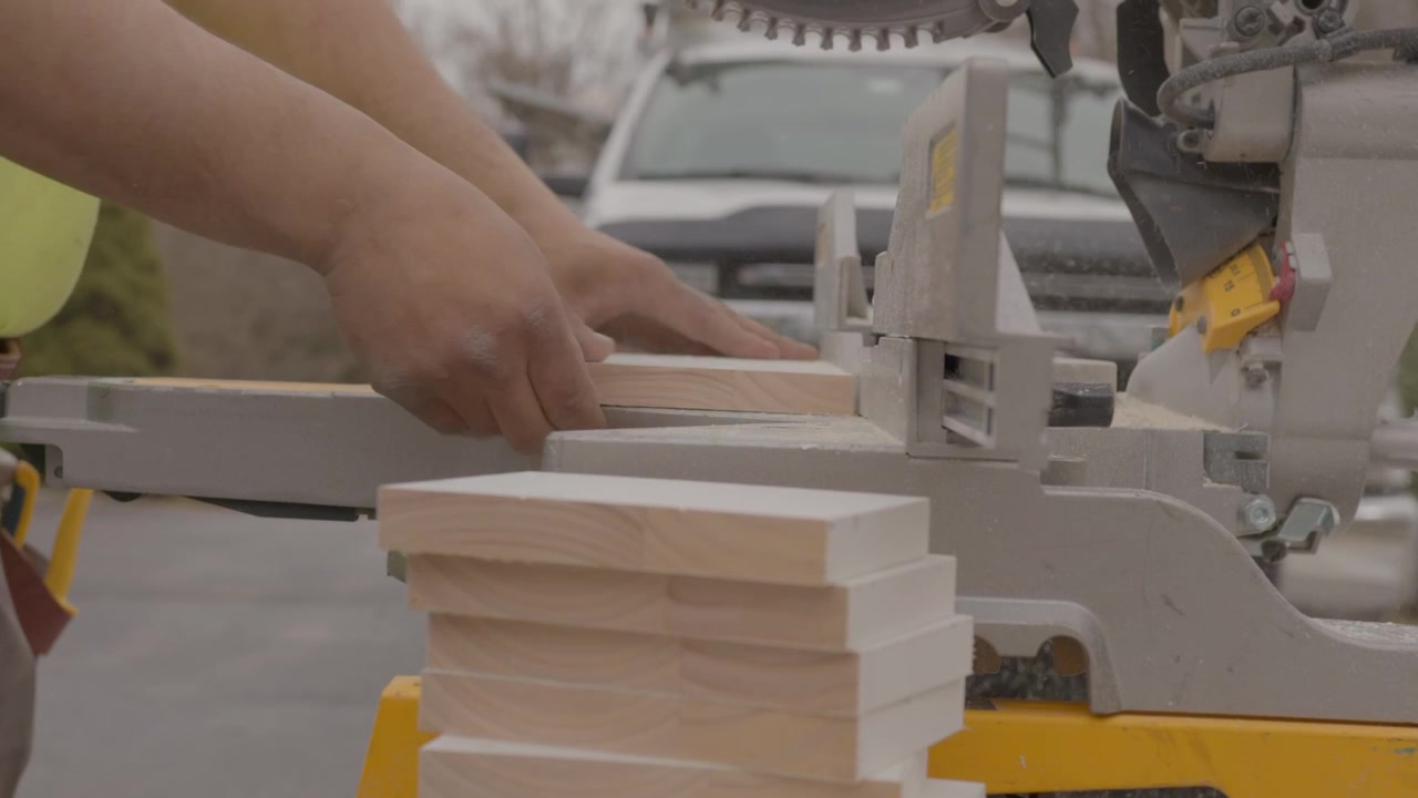 Un uomo sta usando una sega da banco per tagliare blocchi di legno.
