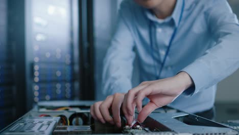 in the modern data center: it engineer wearing protective headphones installs new hardware for server rack. it specialist doing maintenance, running diagnostics and updating hardware.