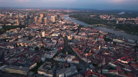 High-aerial-drone-view-of-Bratislava-city-at-sunset-with-Danube-river,-pan