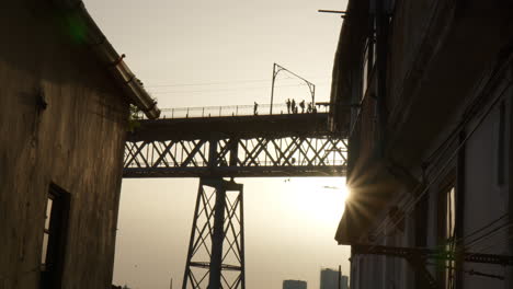 pedestrians across luís i bridge at sunset on vila nova de gaia in oporto, portugal. low angle shot