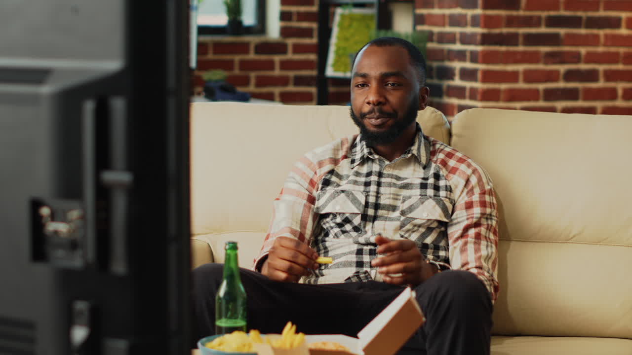 Smiling man eating hamburger with fries and beer