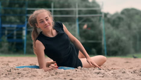 young female athlete dives into the sand and saves a point during beach volleyball match. cheerful caucasian girl jumps and crashes into the white sand during a beach volley tournament.