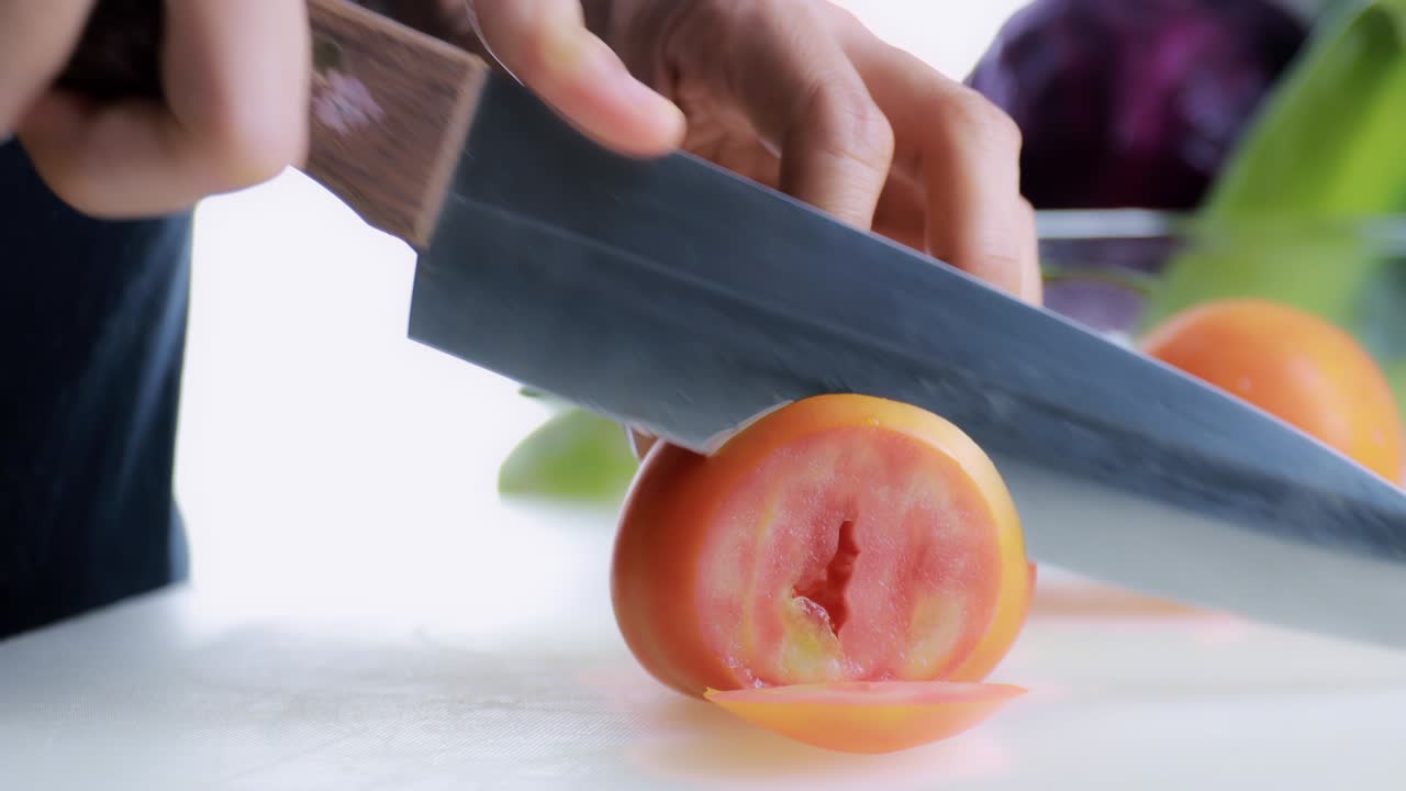 4k 여성 손으로 는 보드에 신선한 토마토를 잘라 여성 손은 기 보드에 칼로 원시 토마토을 원으로 잘라 건강한 음식 개념.