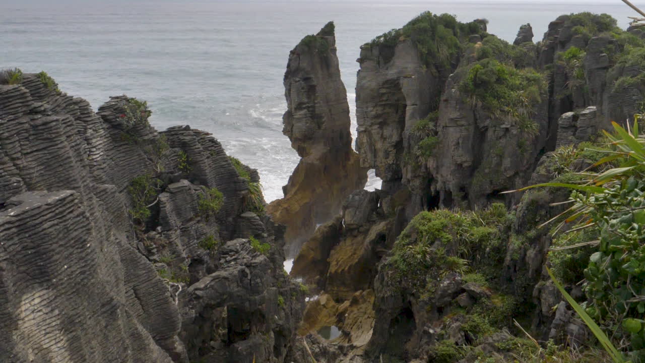 olas en movimiento lento chocan alrededor de una columna de mar y acantilados - punakaiki, nueva zelanda