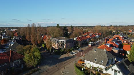 low aerial of beautiful suburban neighborhood with two driving cars and a cyclist on the calm road