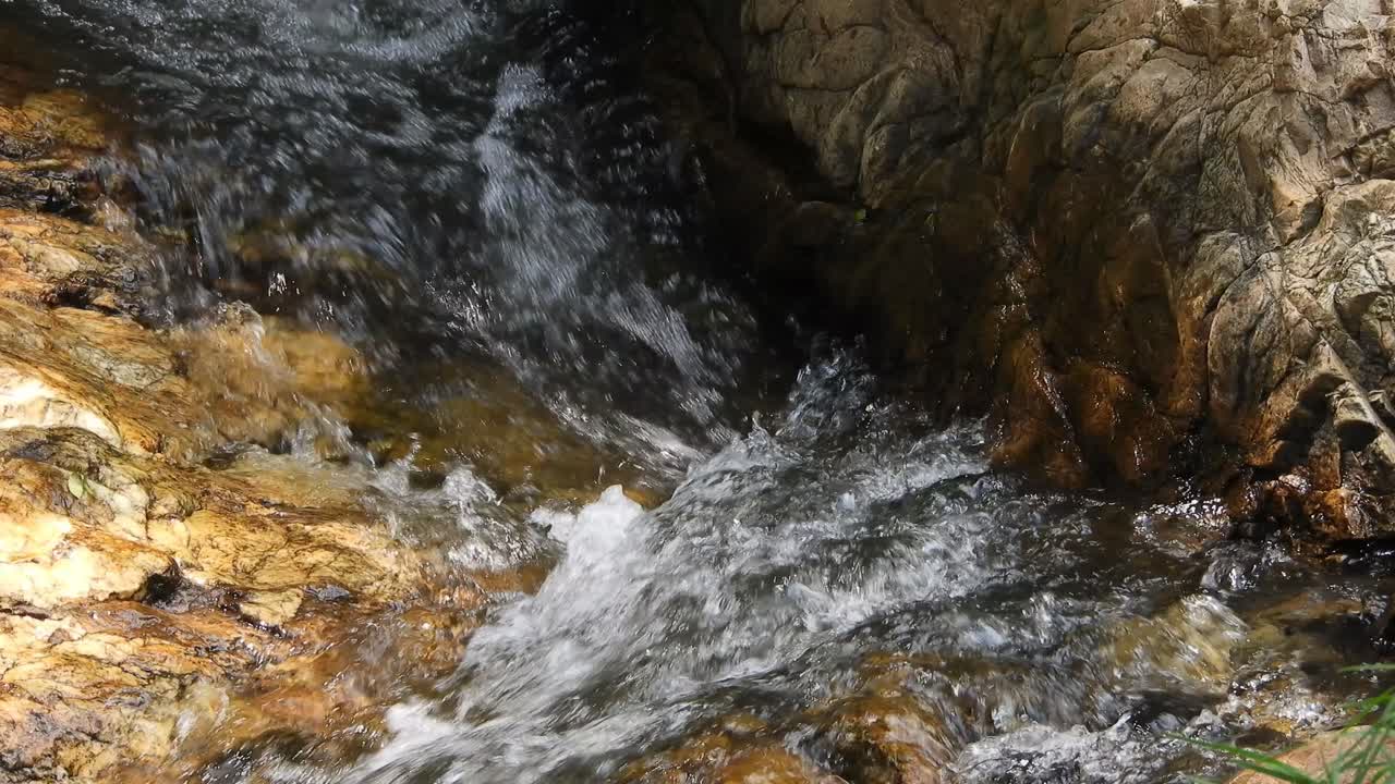 Acqua cristallina e fresca di cascata montana e del fiume Crocodile, scintillante e che scorre su rocce e ciottoli, nei giardini botanici nazionali Walter Sisulu a Roodepoort, Sudafrica