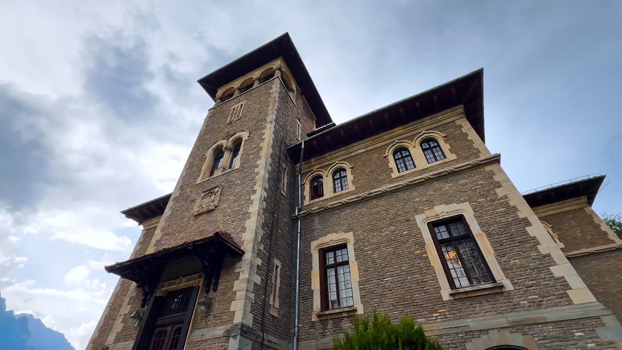 Tower at the façade of the famous Cantacuzino Castle in Busteni, Romania. Low angle view at the building on rainy day