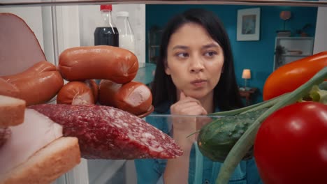 Woman looking inside a refrigerator, choosing food