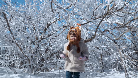 una niña disfruta jugando en la nieve en un soleado día de invierno