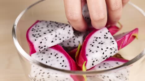 hand picking dragon fruit from a bowl