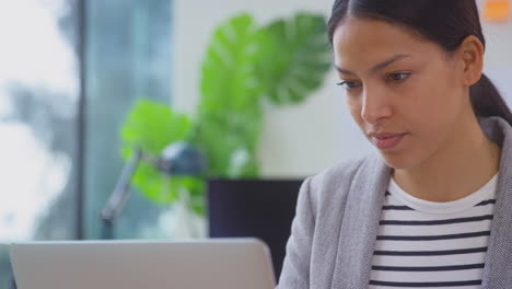 Close-Up-Of-Businesswoman-In-Office-At-Desk-Working-On-Laptop