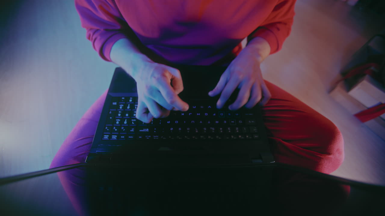 크리스마스 동안 조명 된 집에서 노트북에서 빠르게 타이핑하는 사람