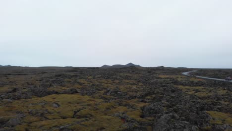 paisaje áspero brumoso con rocas de formación de lava, coche conduciendo por la carretera