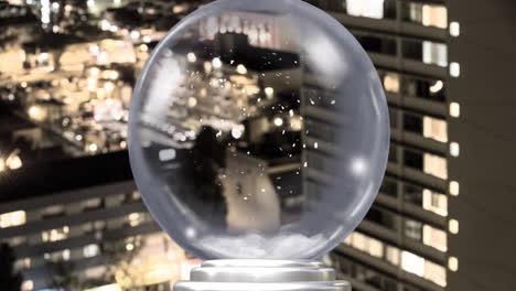 snow globe with falling snow animation over cityscape at night