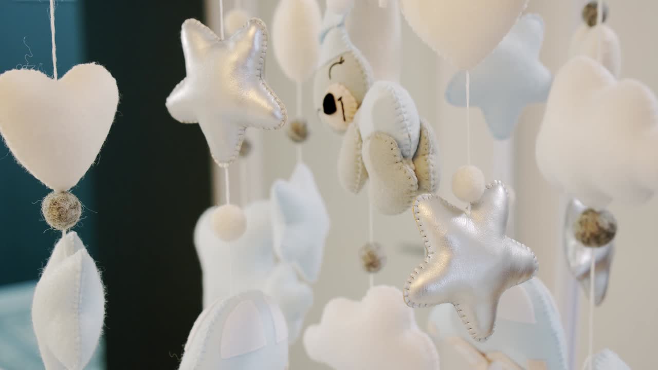 어린이의 부드러운 장난감은 요람 침대 위에서 원으로 회전합니다. 가까이 가십시오. 여전히 카메라