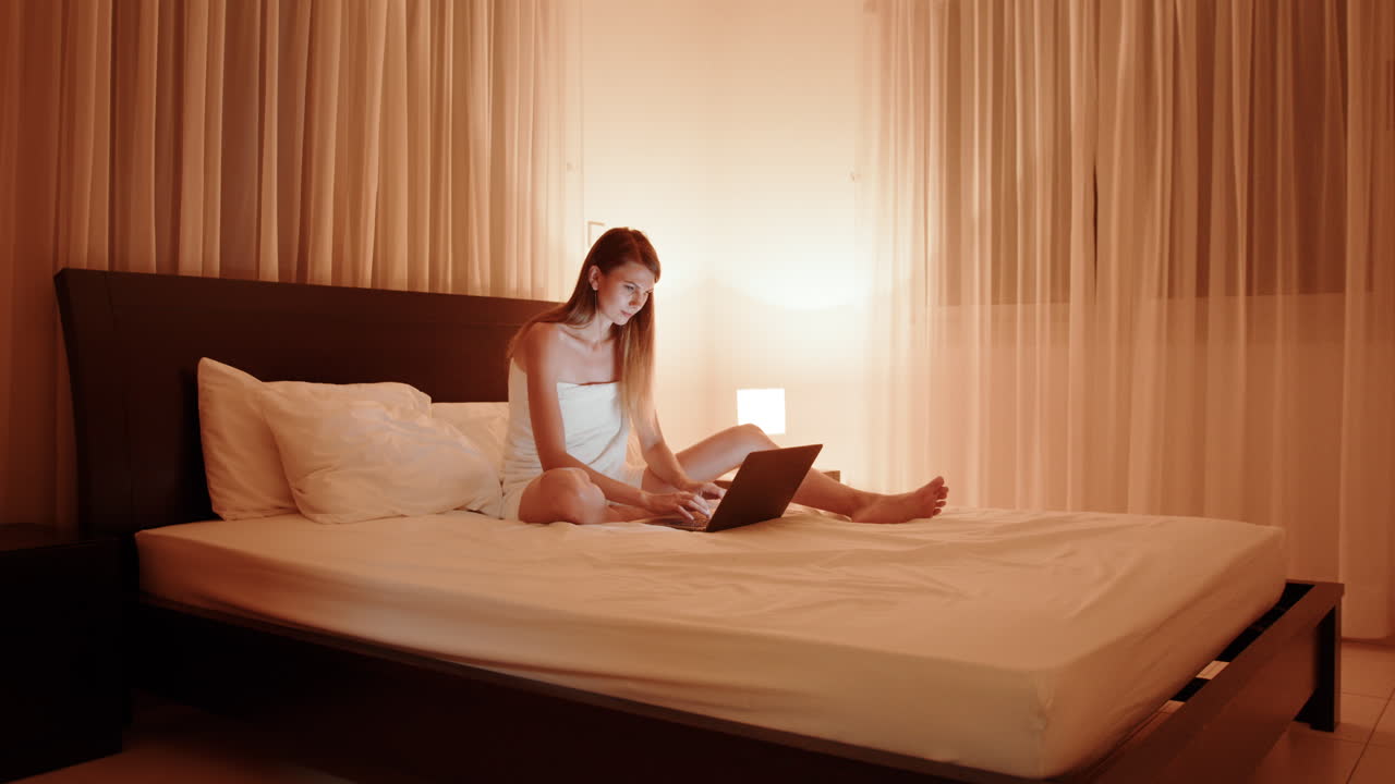 밤에 침대에서 노트북으로 일하는 여자
