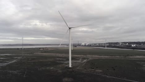 Sustainable-electrical-wind-turbines-spinning-on-England-farmland-slow-pull-back