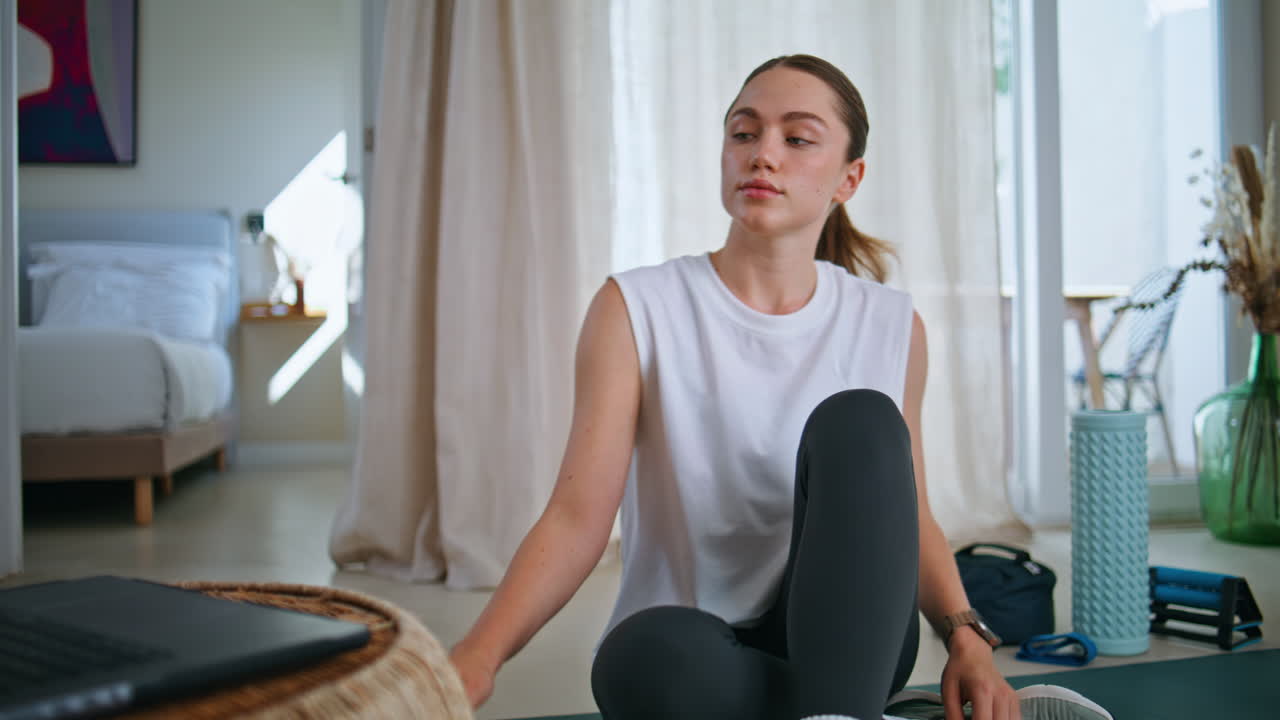 Woman browsing fitness tutorial video at laptop preparing to home workout