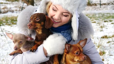 mujer jugando con sus perros pequeños fuera del invierno
