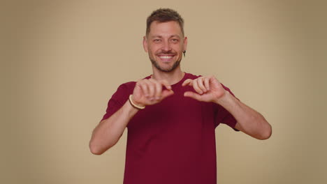 Smiling-bearded-handsome-young-man-makes-heart-gesture-demonstrate-love-sign-expresses-good-feelings