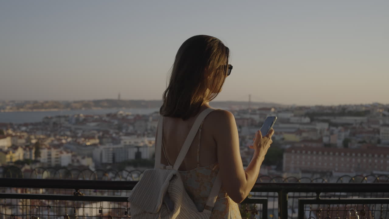 Woman taking a photo of a city view at sunset
