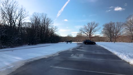 a couple bycicles driving on a road near a forest during a sunny, chilly and clear-skies afternoon