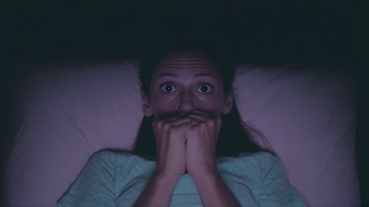 A startled individual lies awake at night, experiencing intense fear and anxiety, captured in two frames showcasing her startled expression, with hands covering her mouth