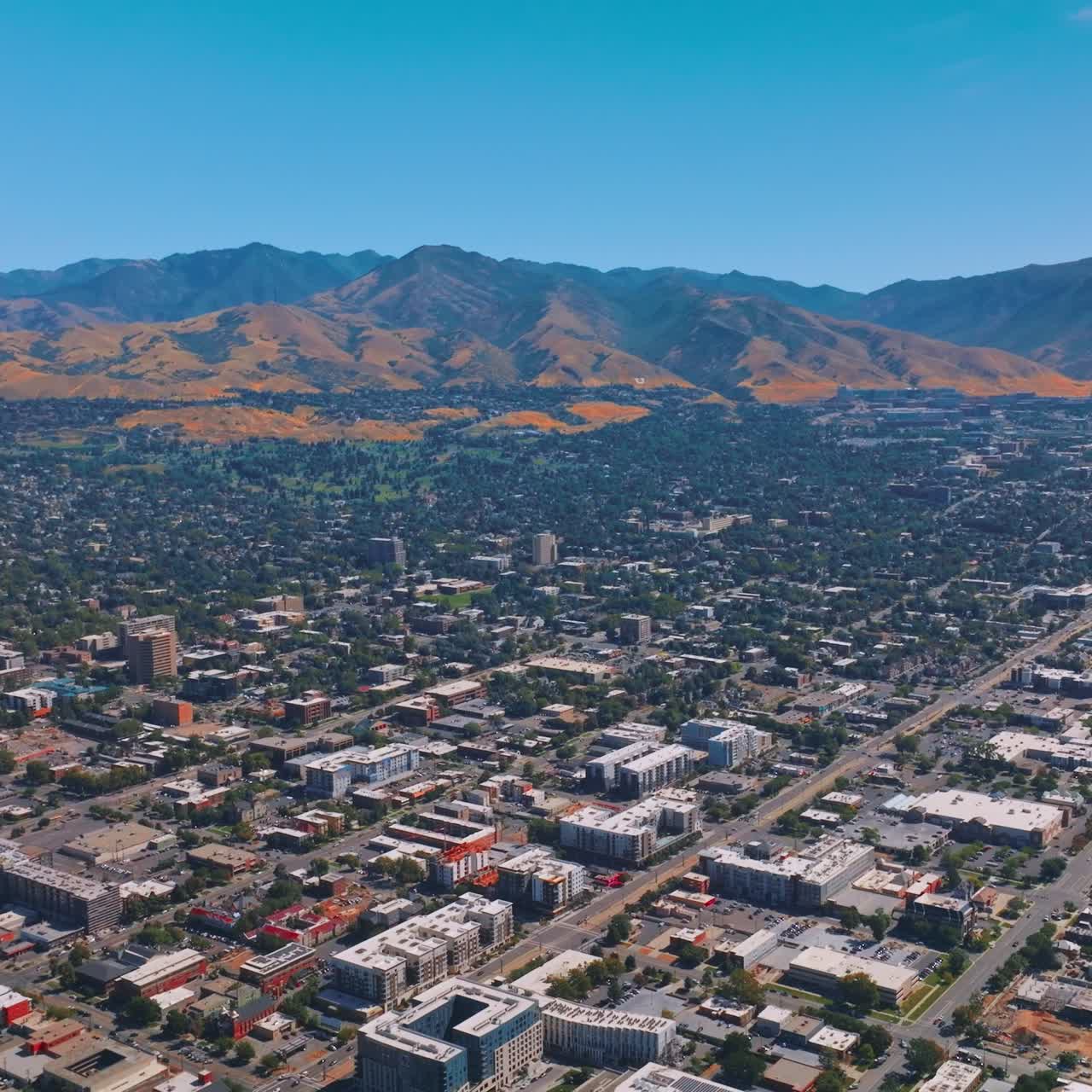 Helicopter flying over the green city on sunny daytime. Mountains of Utah with wonderful Salt Lake City at the foot. Top view