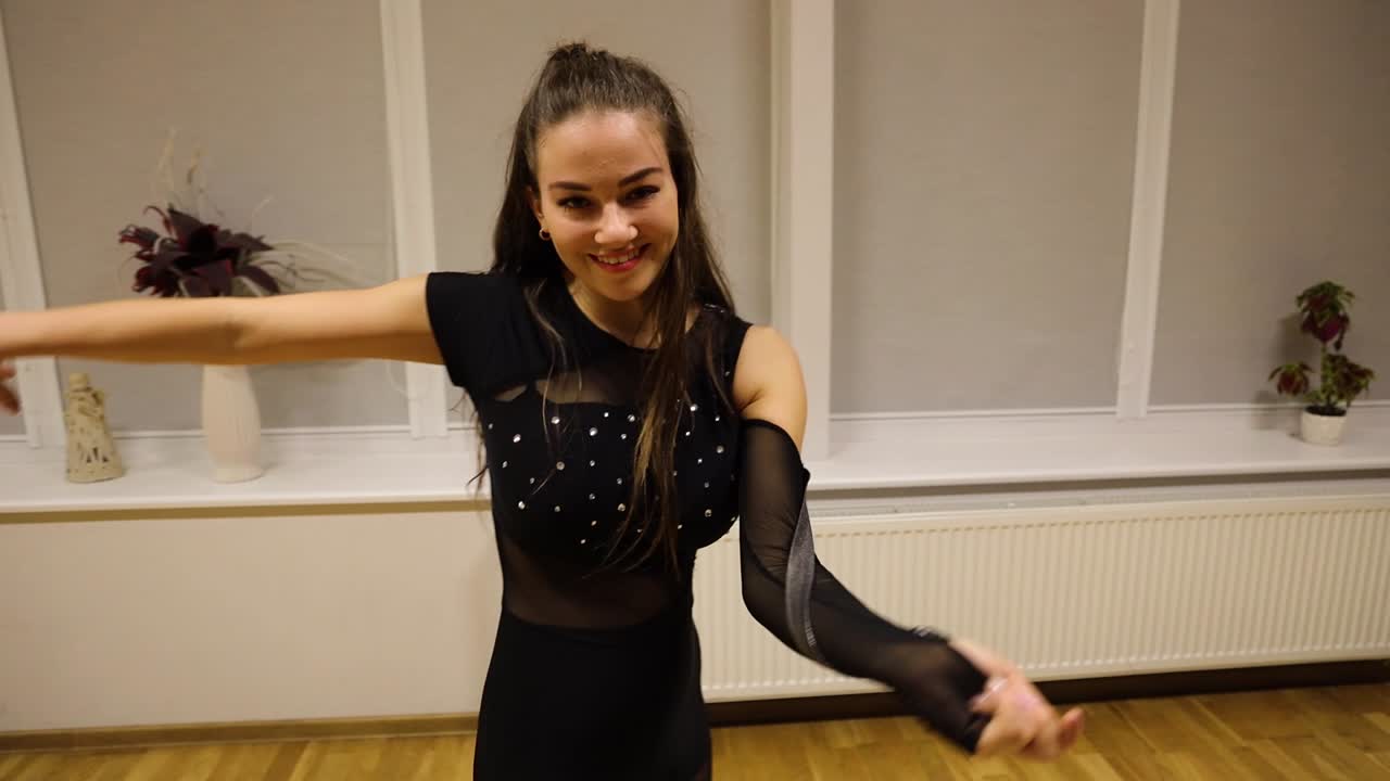 Young female dancer having fun and smiling while dancing a modern choreography in an empty studio