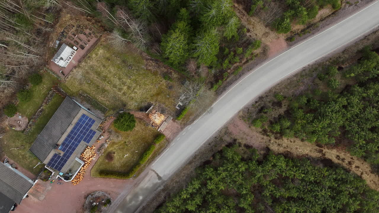 Hyperlapse drone shot of a man cutting firewood at a solar powered house, spring