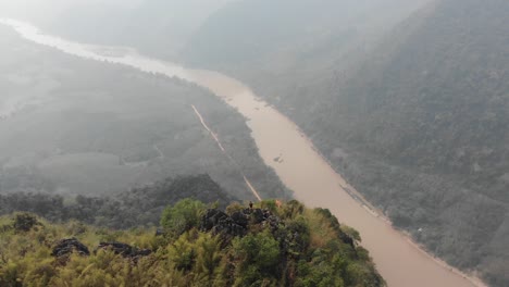 aerial of remote village and mountains landscape with hills and river in muang ngoy, typical settlement in laos