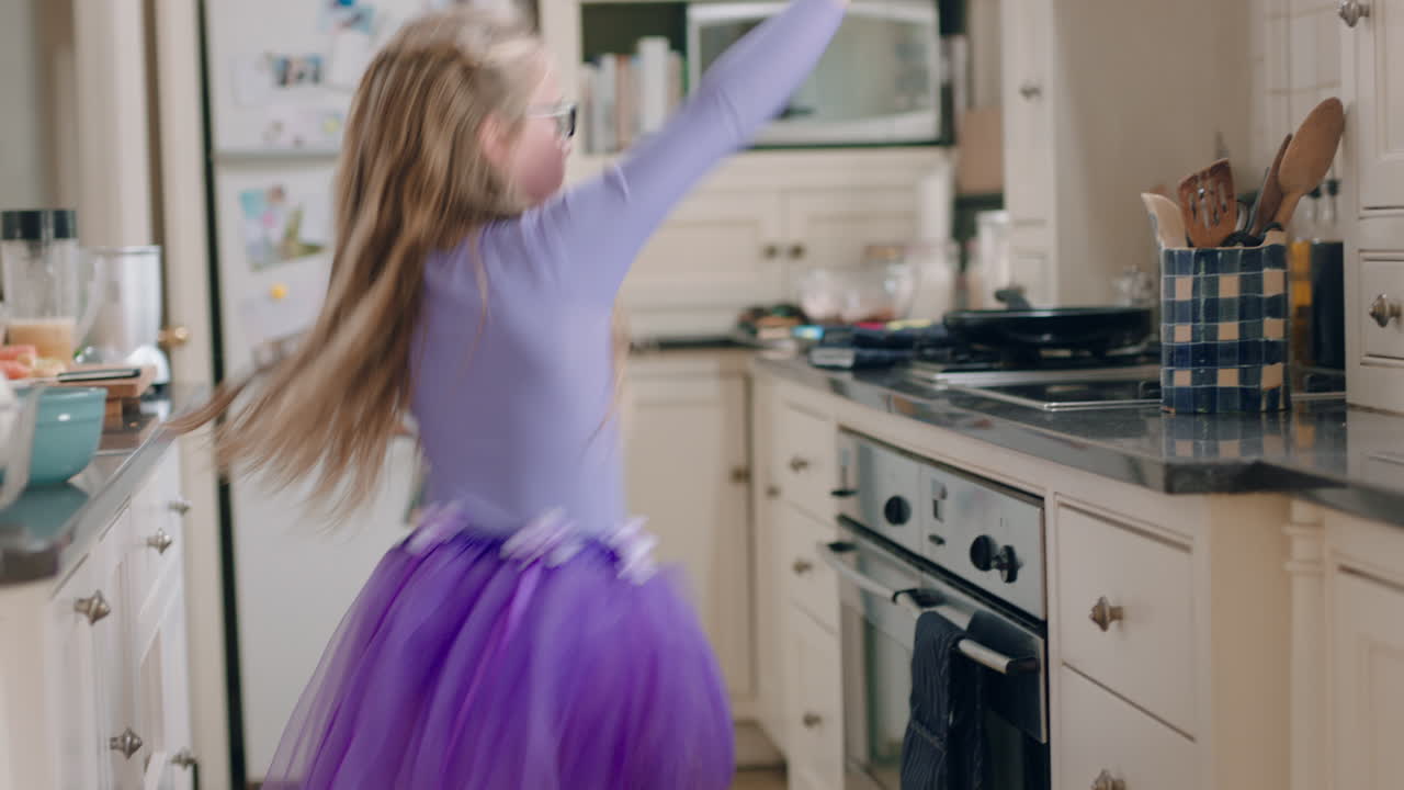 una bailarina feliz bailando en la cocina con un tutu púrpura divirtiéndose realizando movimientos de baile divertidos disfrutando de la celebración del fin de semana en casa
