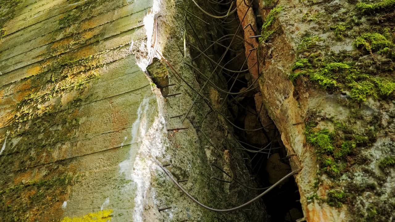 Close up cracked concrete bunker with exposed steel bars and moss at Wolfs Lair