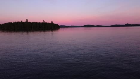 Picturesque-evening-dusk-blue-hour-aerial-over-calm-lake-in-Sweden