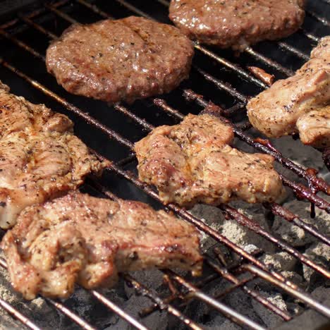 sabrosa carne de hamburguesa y cerdo a la parrilla en video de cámara lenta de barbacoa caliente humeante
