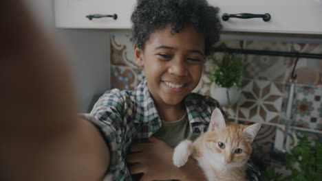 a boy taking a selfie with his cat in a kitchen